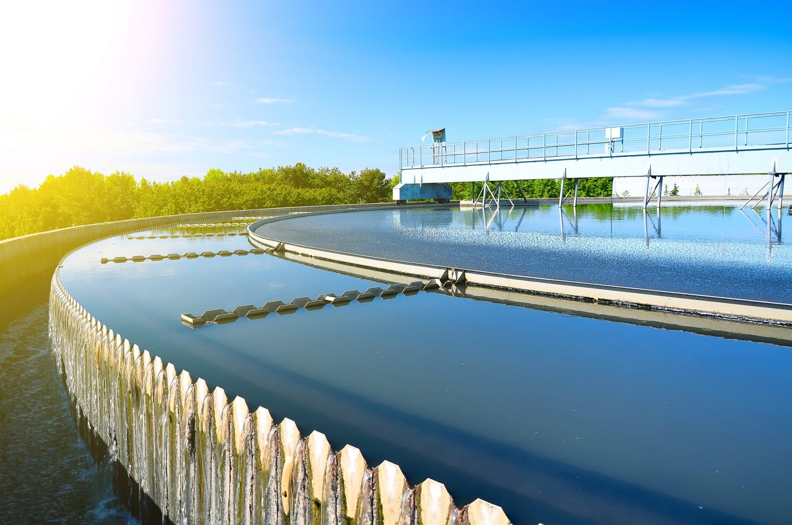 Water treatment facility with a wooden walkway over a large body of clear blue water